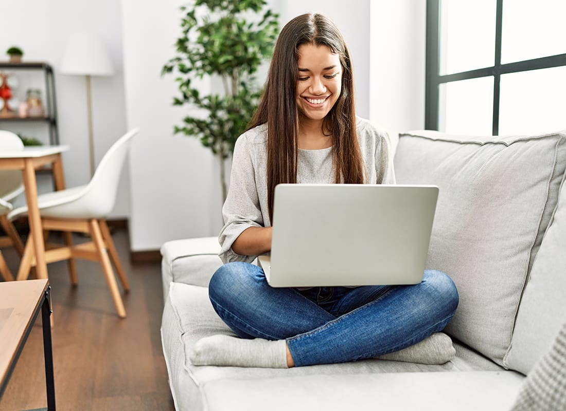 Read Our Reviews - Young Woman Sitting on Her Sofa Reading on Her Laptop